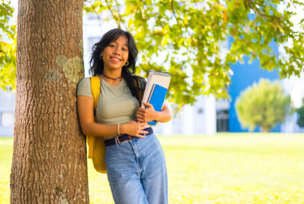 Asian girl on campus, smiling at college under tree